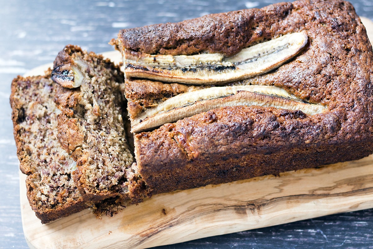 banana bread on wooden board with two slices cut