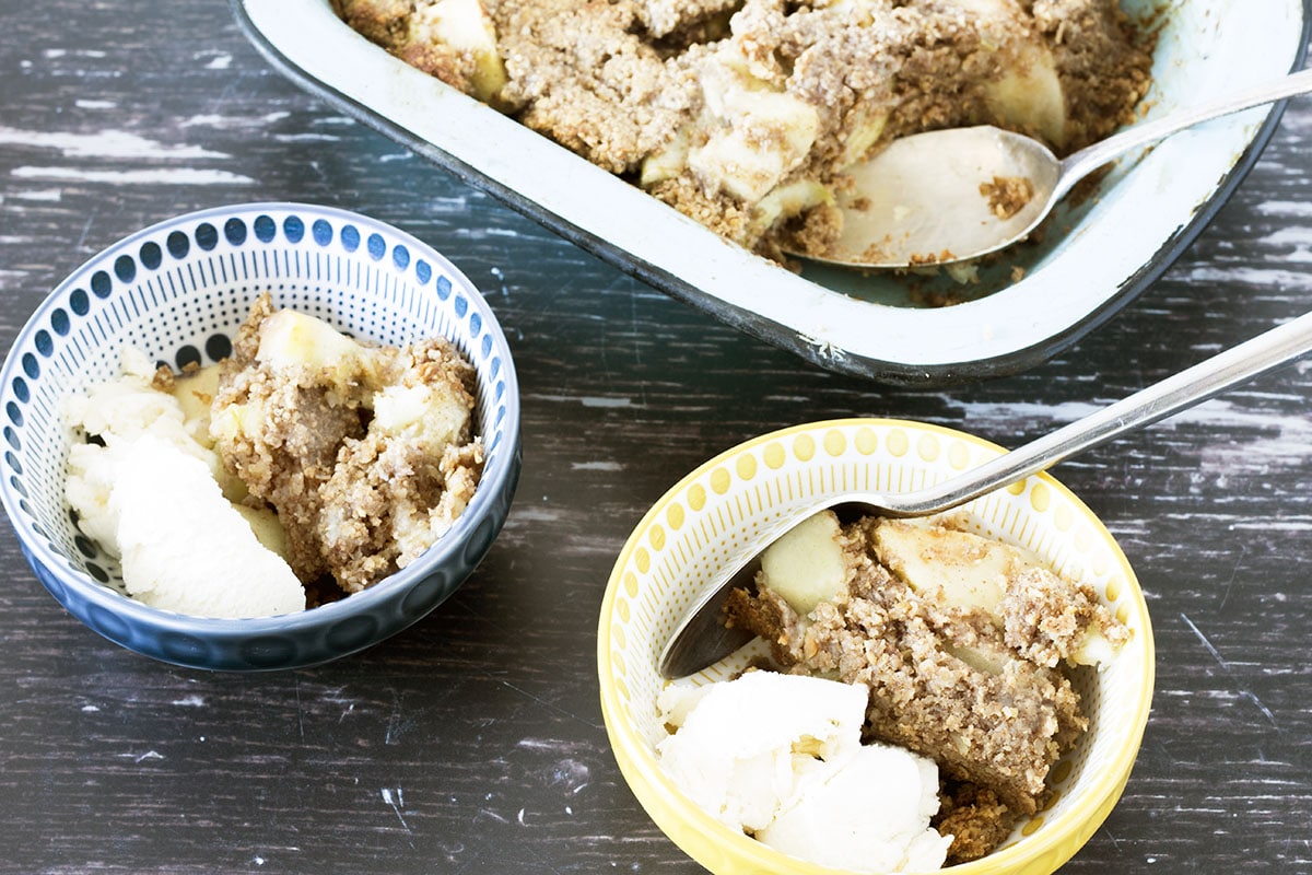 healthy apple crumble in bowls with blue dish in background