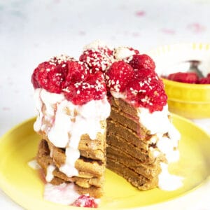 stack of sweet potato pancakes on yellow plate with yoghurt and raspberries