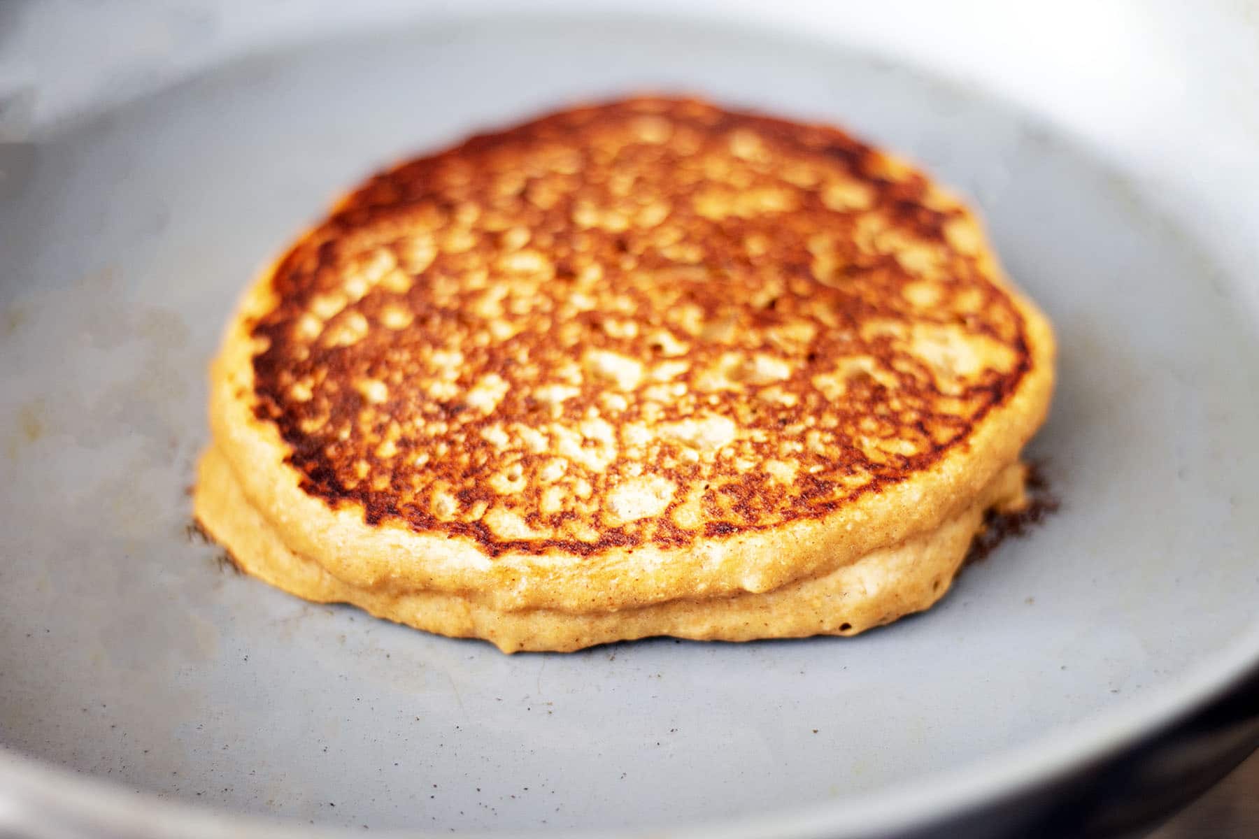 sweet potato pancake cooking on grey pan