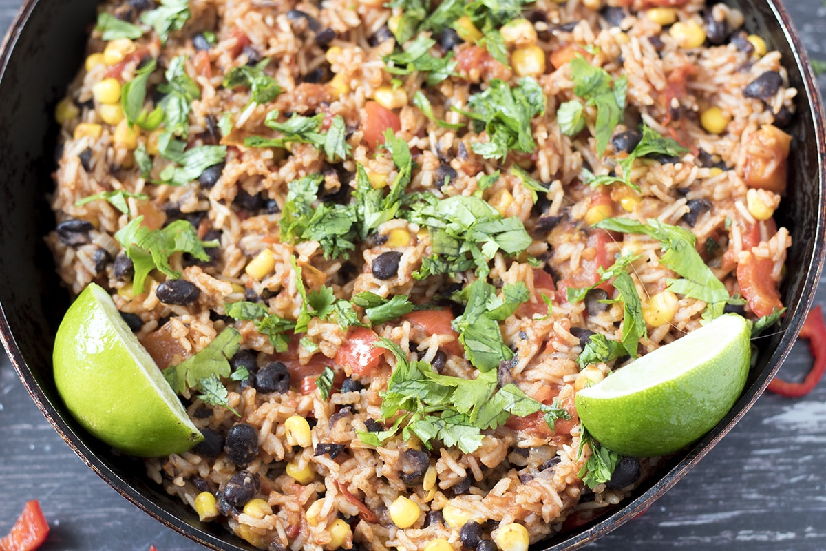 Close up of Mexican spiced rice in pan with coriander and lime