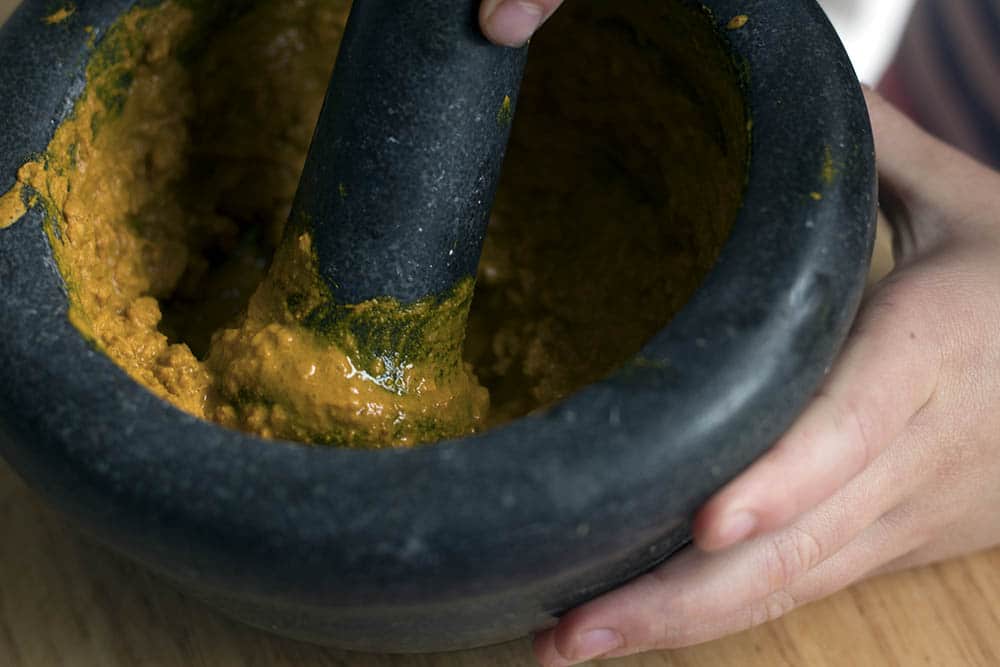 child making curry paste in pestle and mortar
