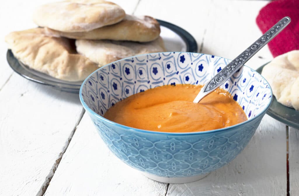 red pepper dip in bowl with flatbreads