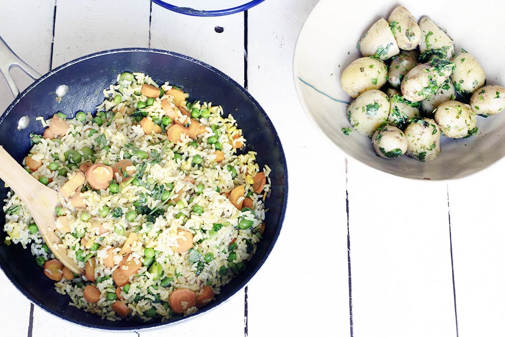 vegetable pilau rice in pan with new potatoes in bowl