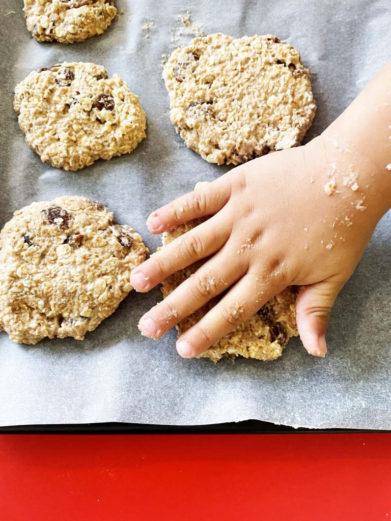 child's hand flattening cookies