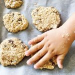 child's hand flattening cookies