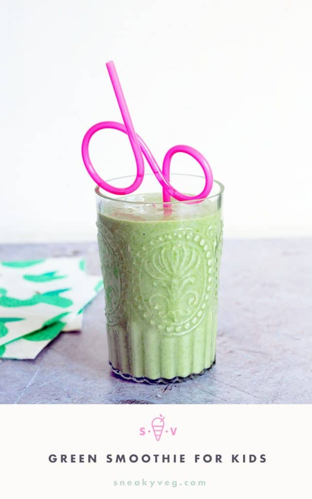green smoothie in glass with pink straw
