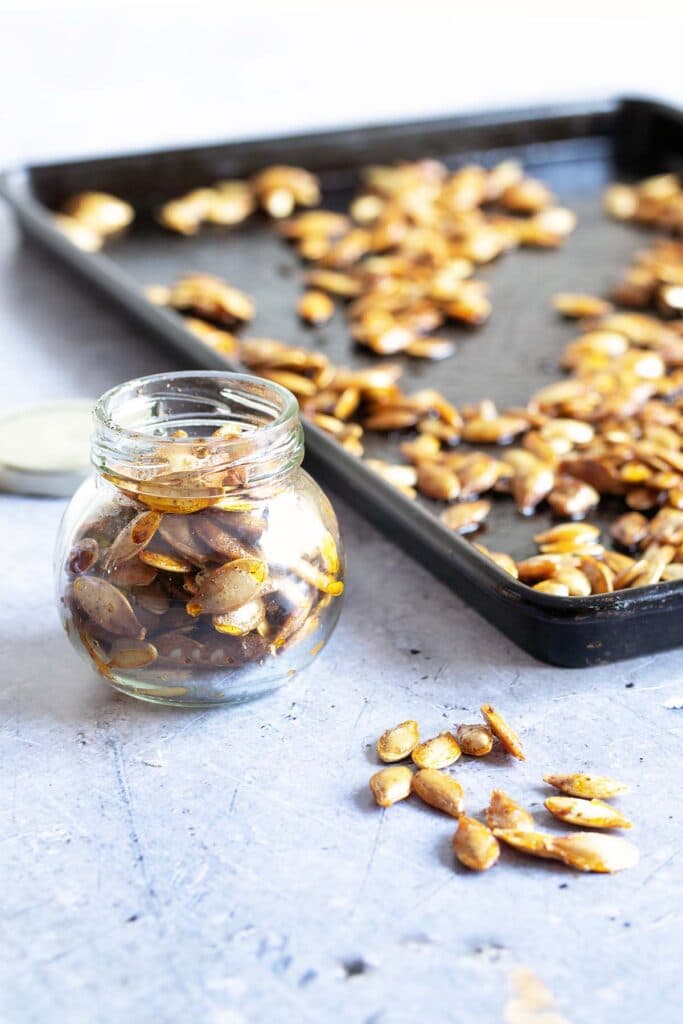 pumpkin seeds in glass year with baking tray in background