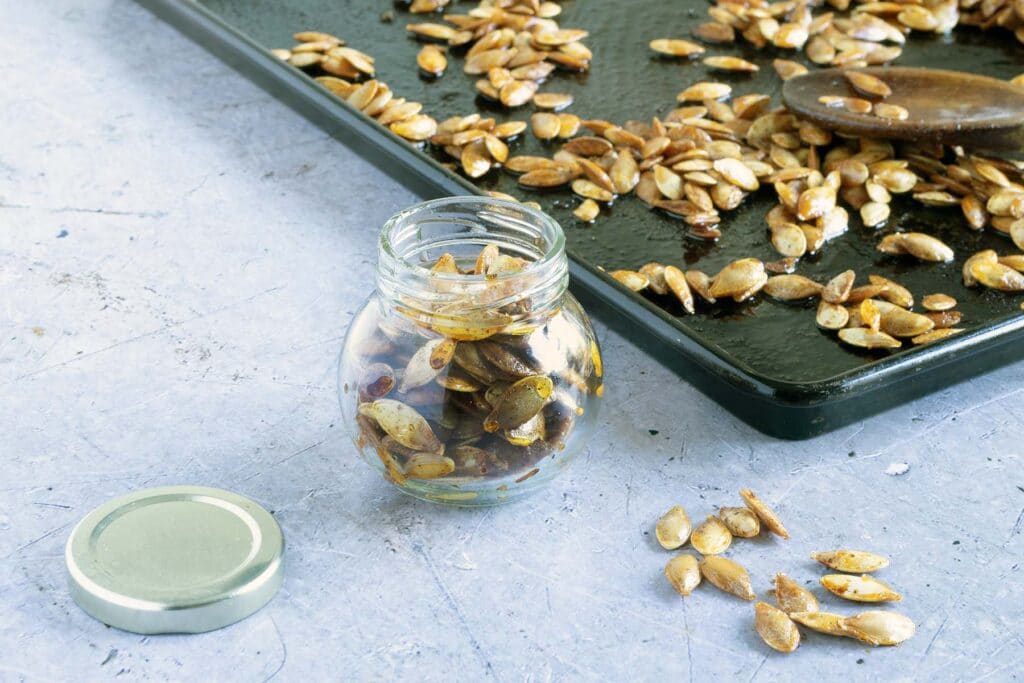 pumpkin seeds in glass year with baking tray in background