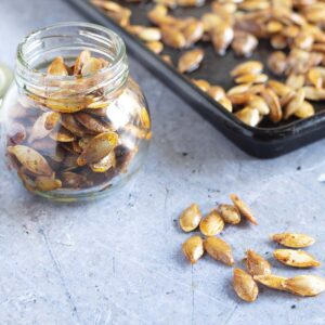 pumpkin seeds in glass year with baking tray in background