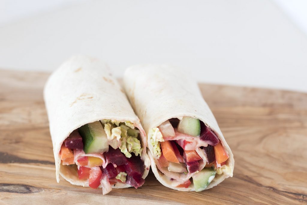 healthy tortilla wraps with rainbow vegetables on brown board