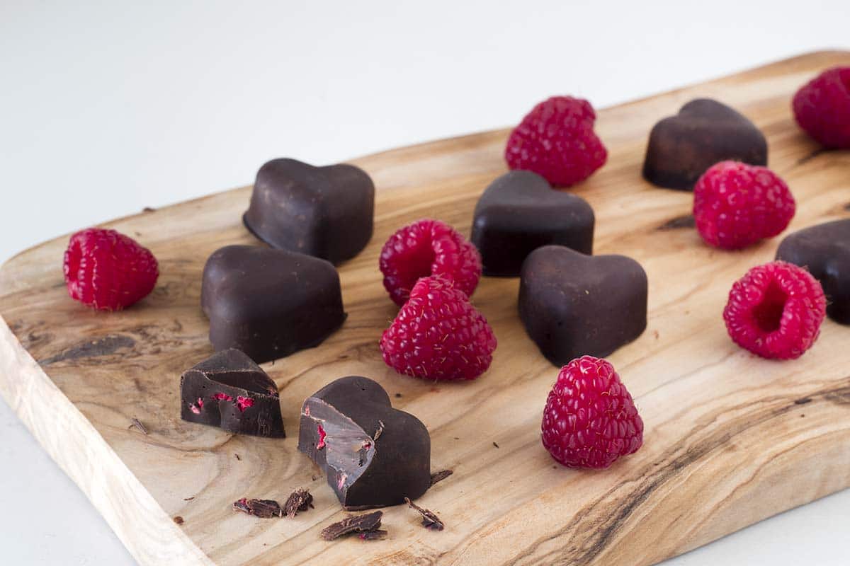 Vegan raspberry and chocolate hearts on wooden board