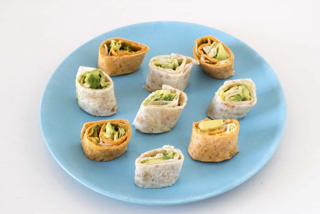 avocado, hummus and lettuce wrap pinwheels on blue plate