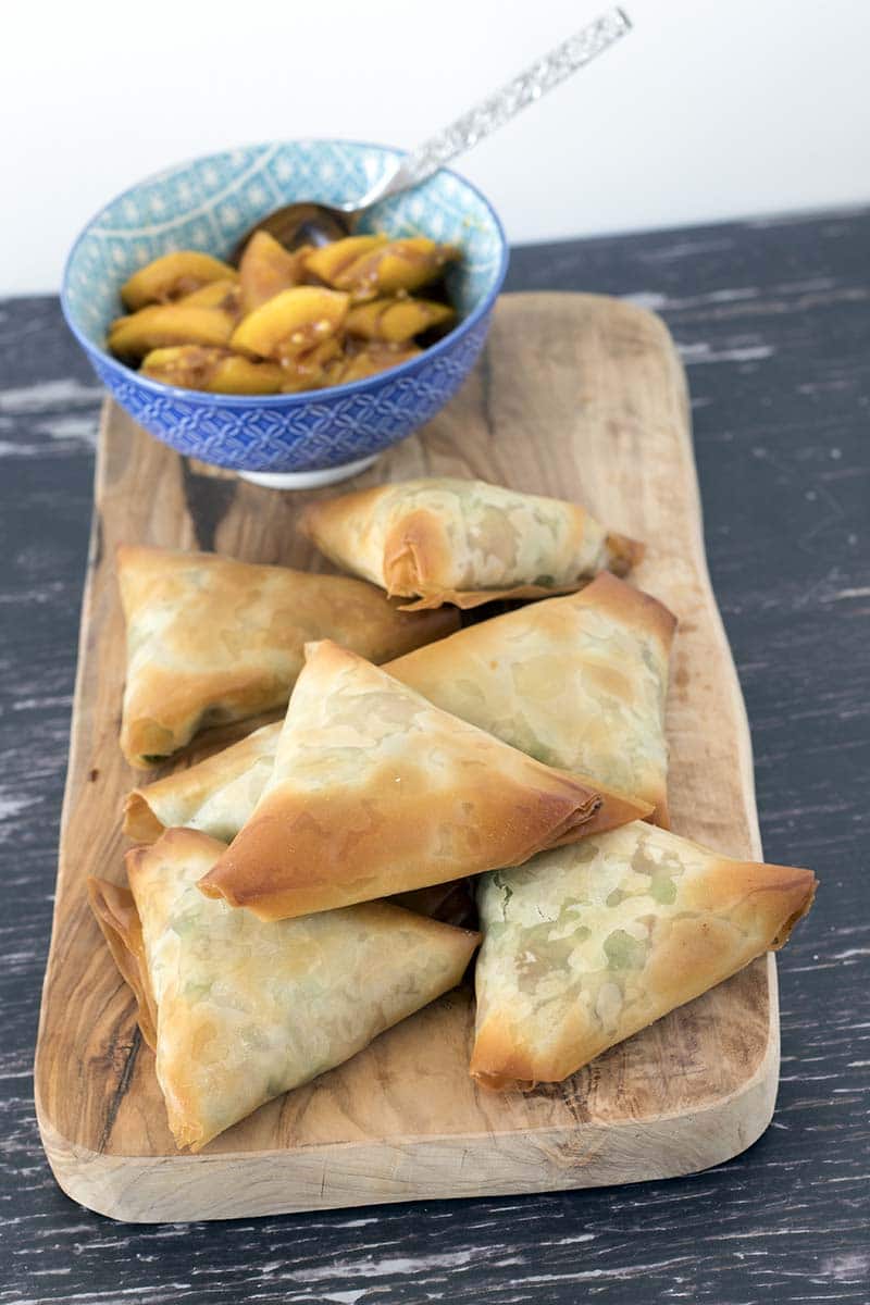 vegetable samosas on board with pickle in blue bowl