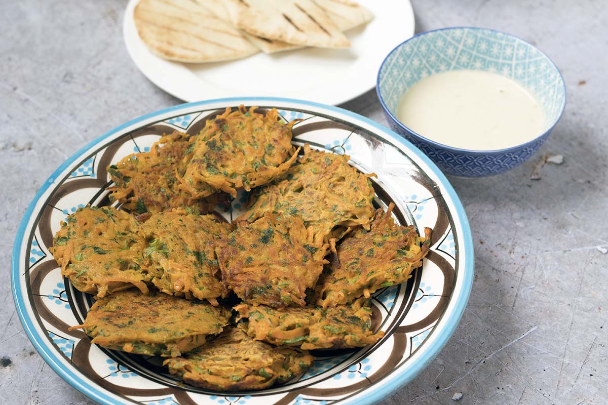 Carrot and herb fritters on plate with tahini and pitta