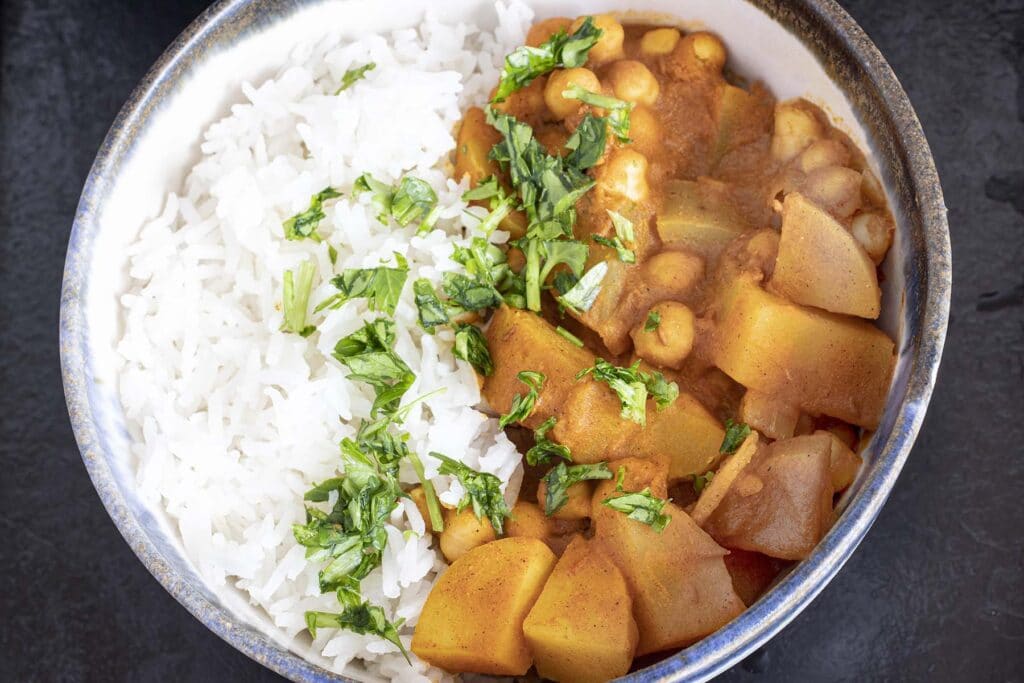 overhead shot of potato chickpea curry in bowl with rice