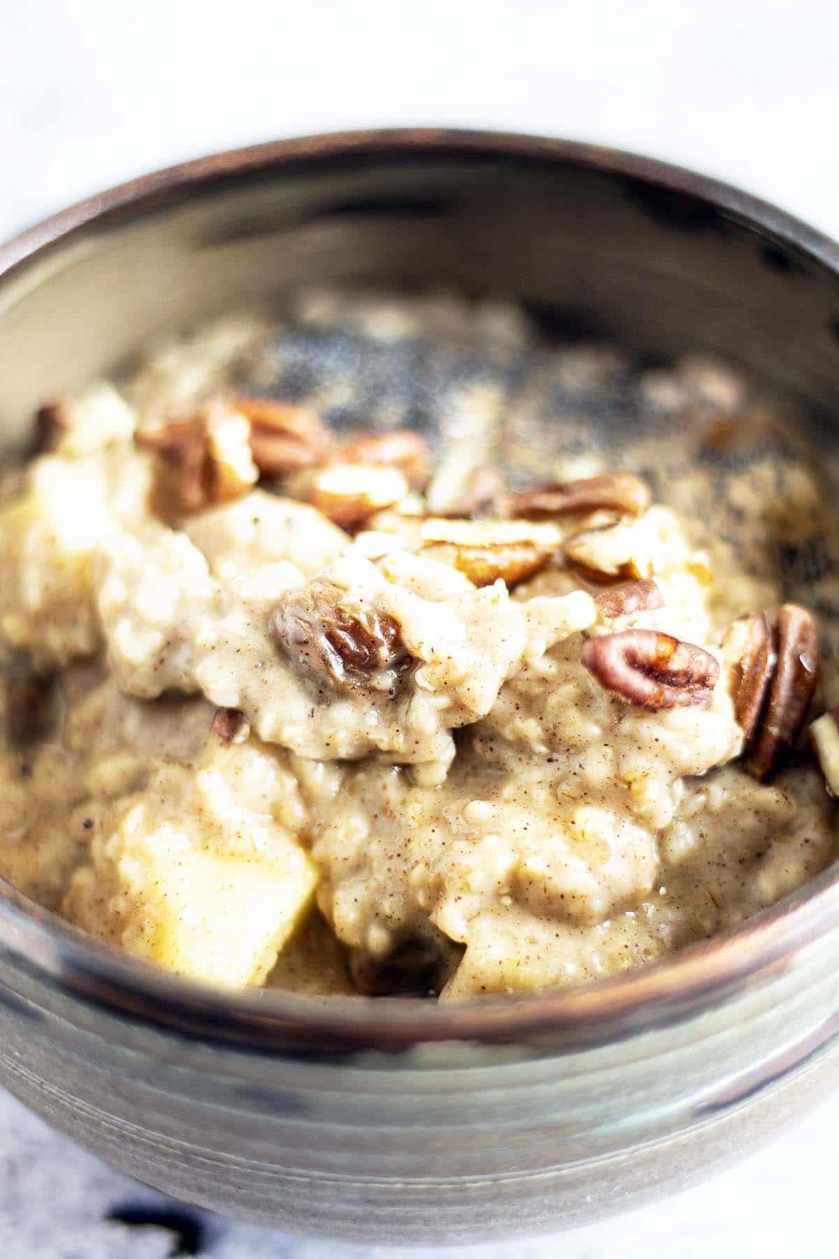 apple and cinnamon porridge in bowl topped with pecans