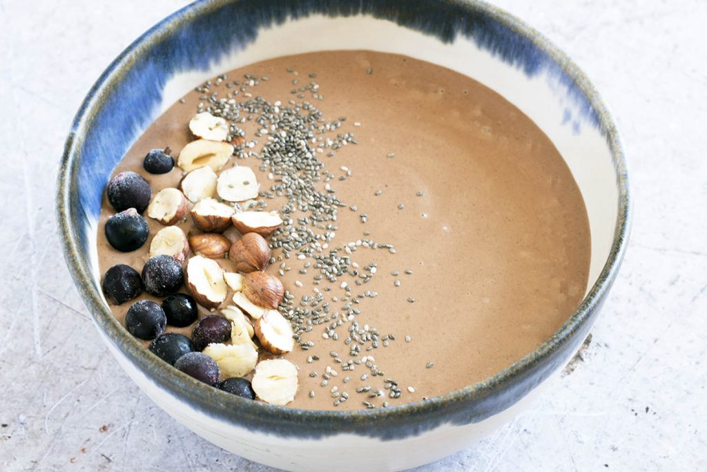 hazelnut and chocolate smoothie bowl in blue and white bowl with toppings