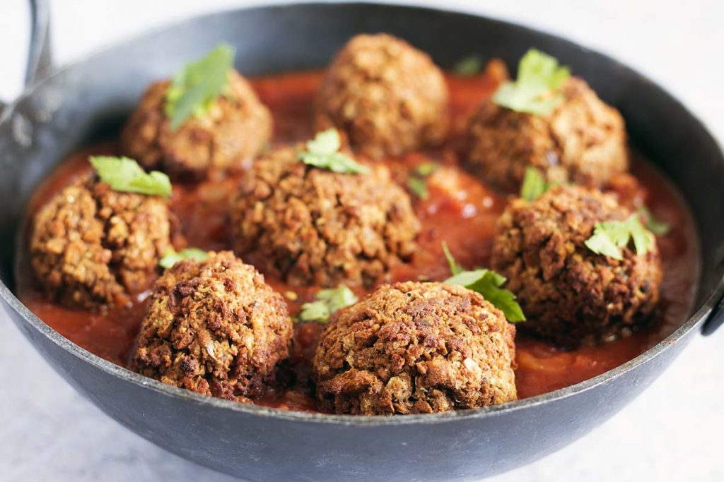 vegan meatballs in black dish with tomato sauce