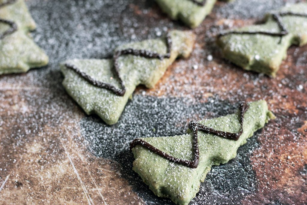 green christmas tree cookies with icing sugar snow and christmas decorations