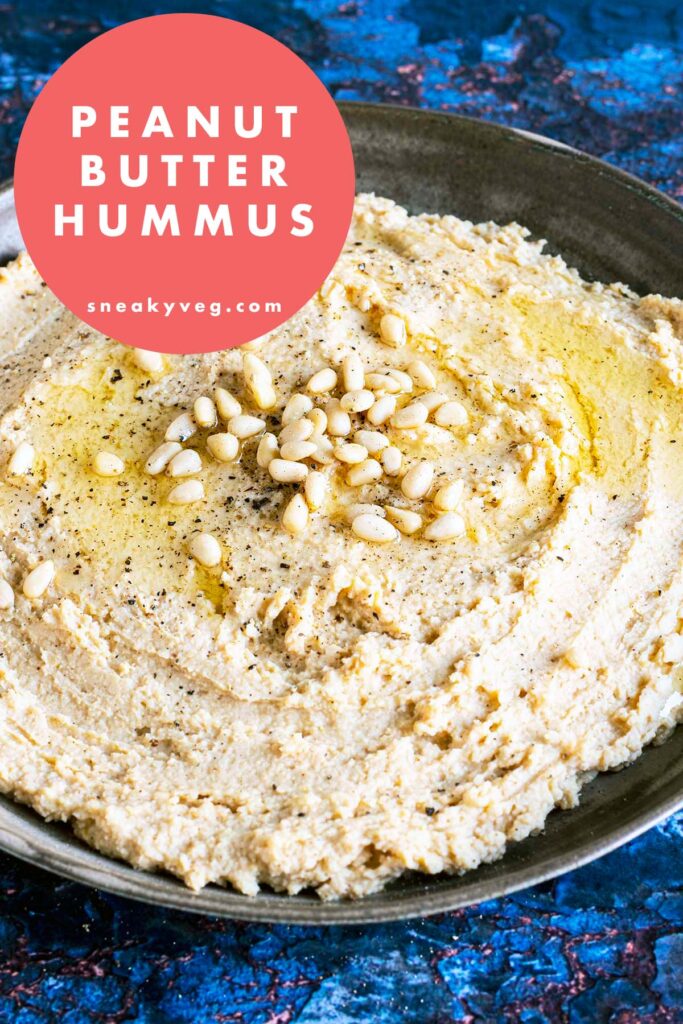 peanut butter hummus on plate topped with oil and pine nuts