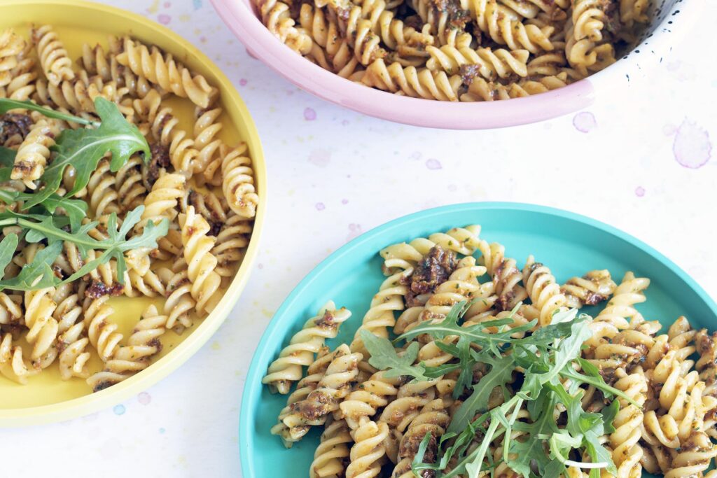 sundried tomato pesto with pasta and rocket on colourful plates