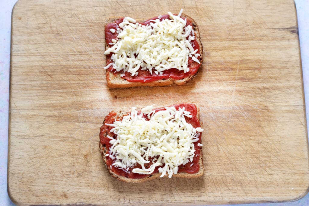 two slices of toast topped with tomato sauce and grated cheese