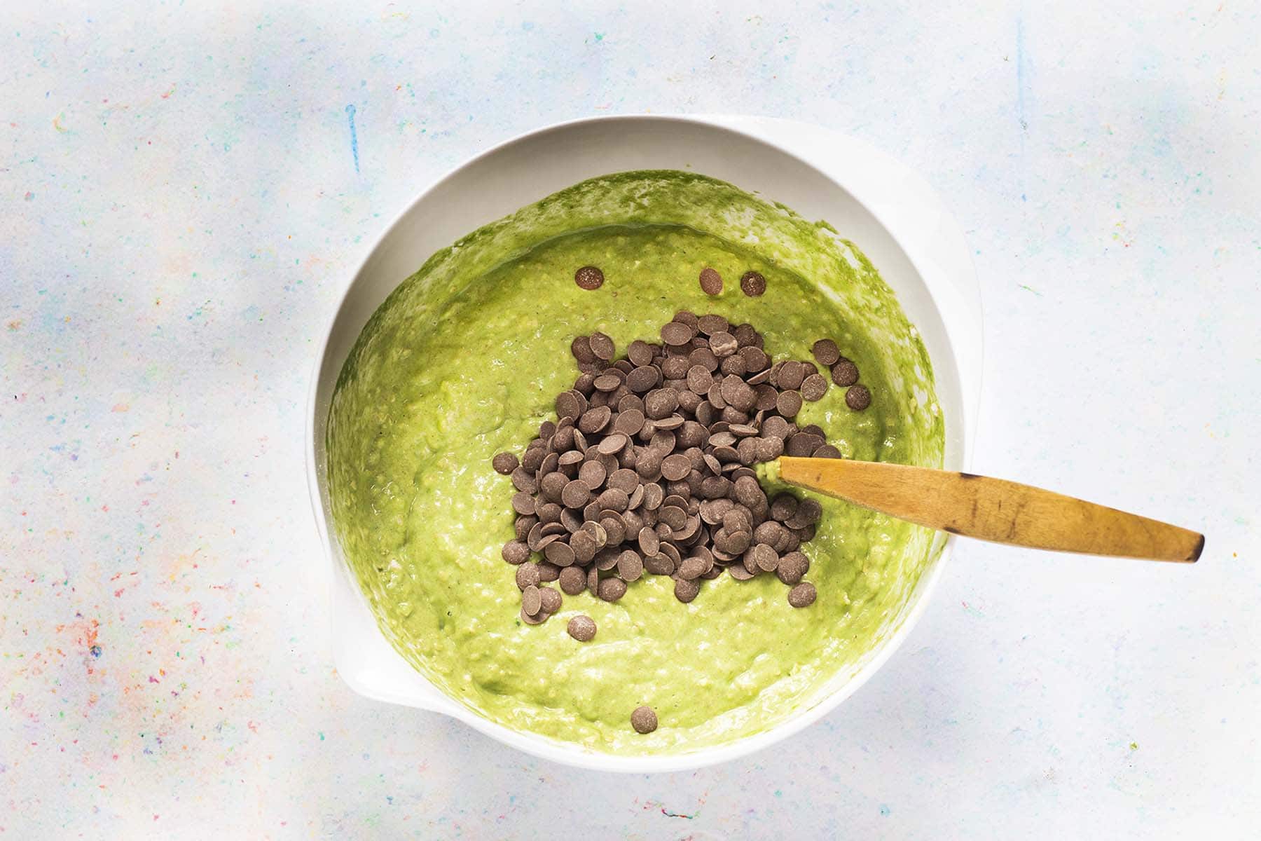spinach muffins batter in white bowl with chocolate chips