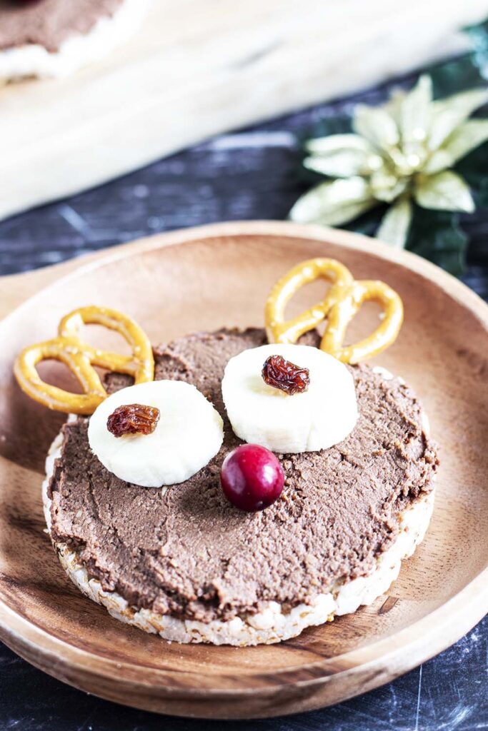 rice cake reindeer face with chocolate hummus, fruit and pretzels