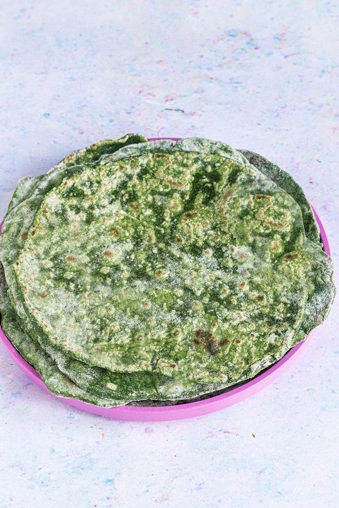stack of spinach wraps on pink plate