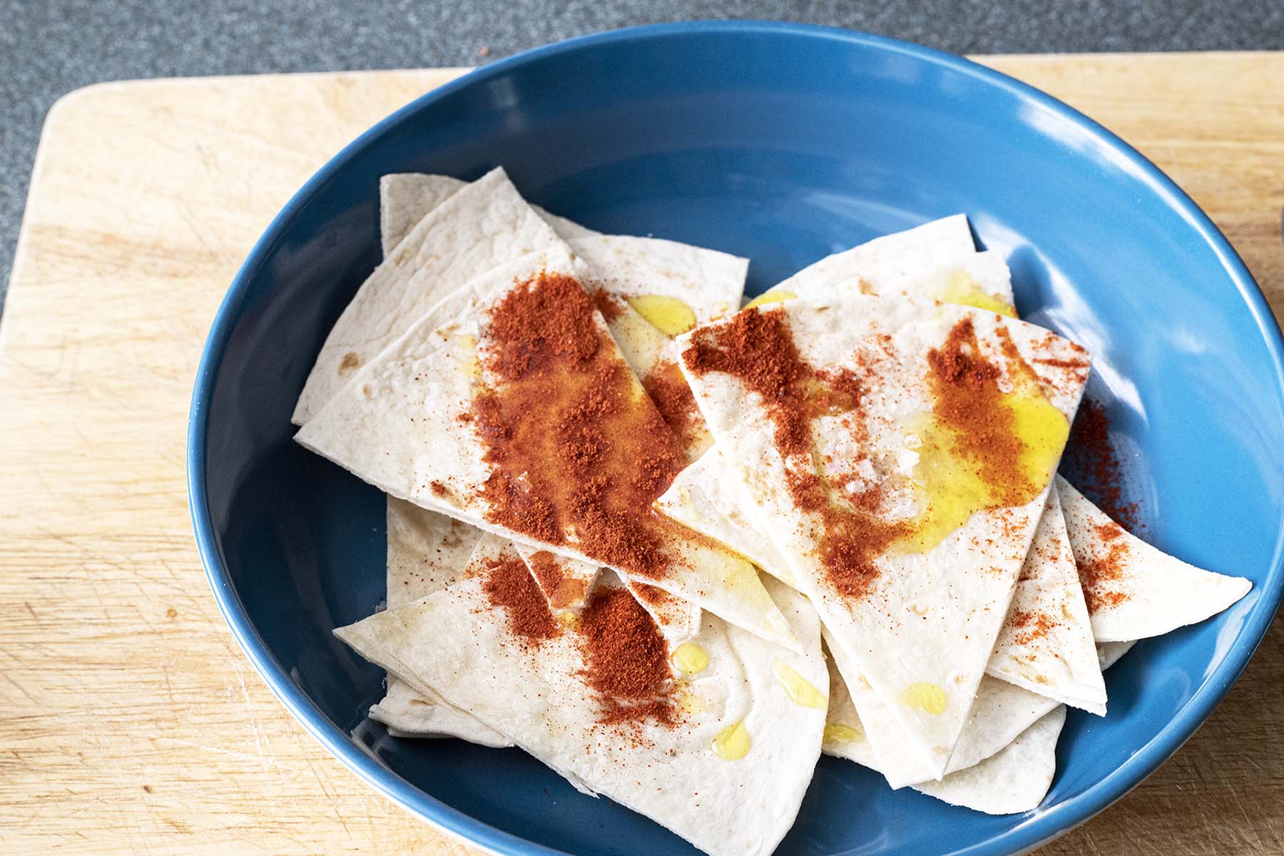 wraps sliced into triangles with oil and paprika in blue bowl