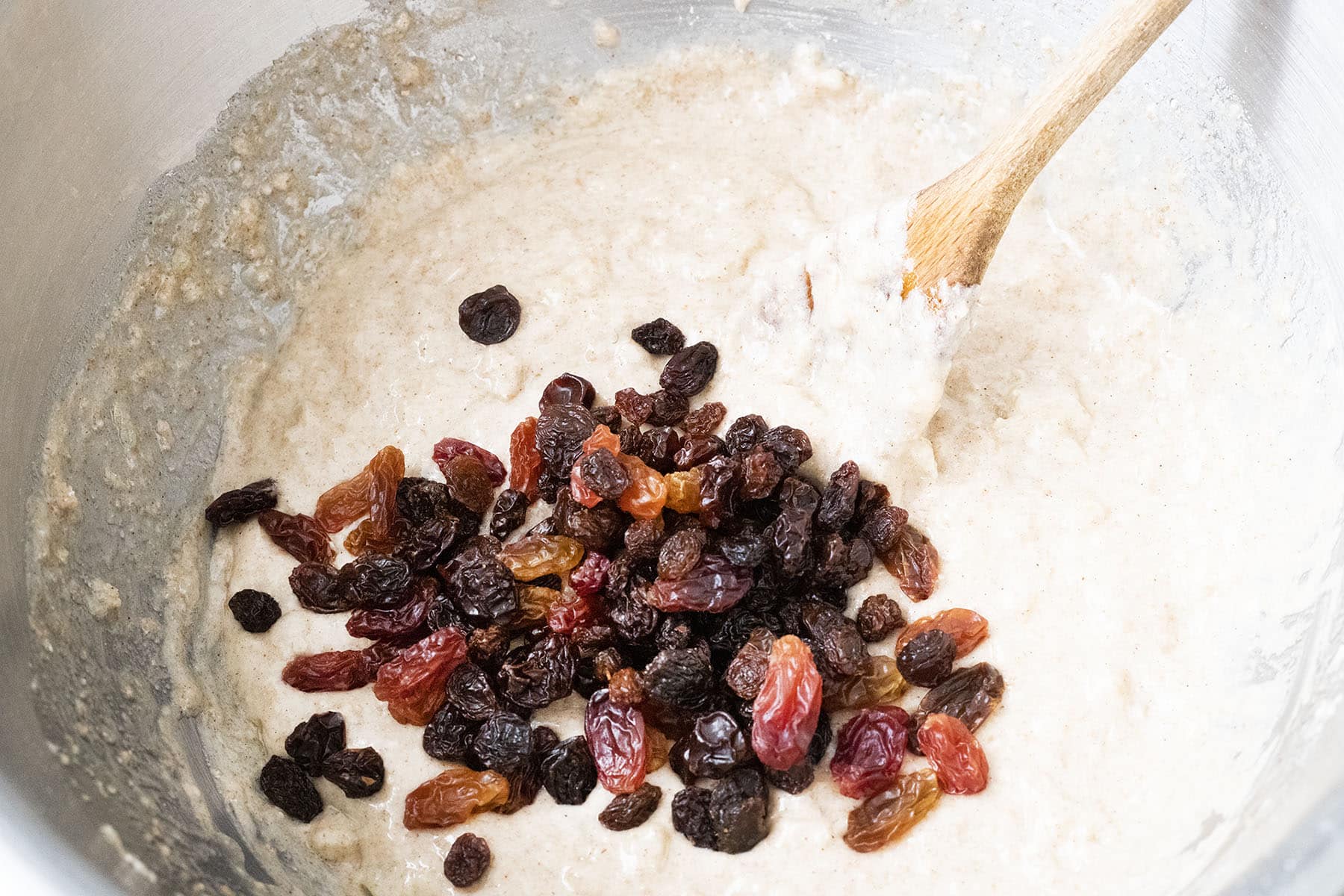cake mix in bowl with wooden spoon and raisins on top