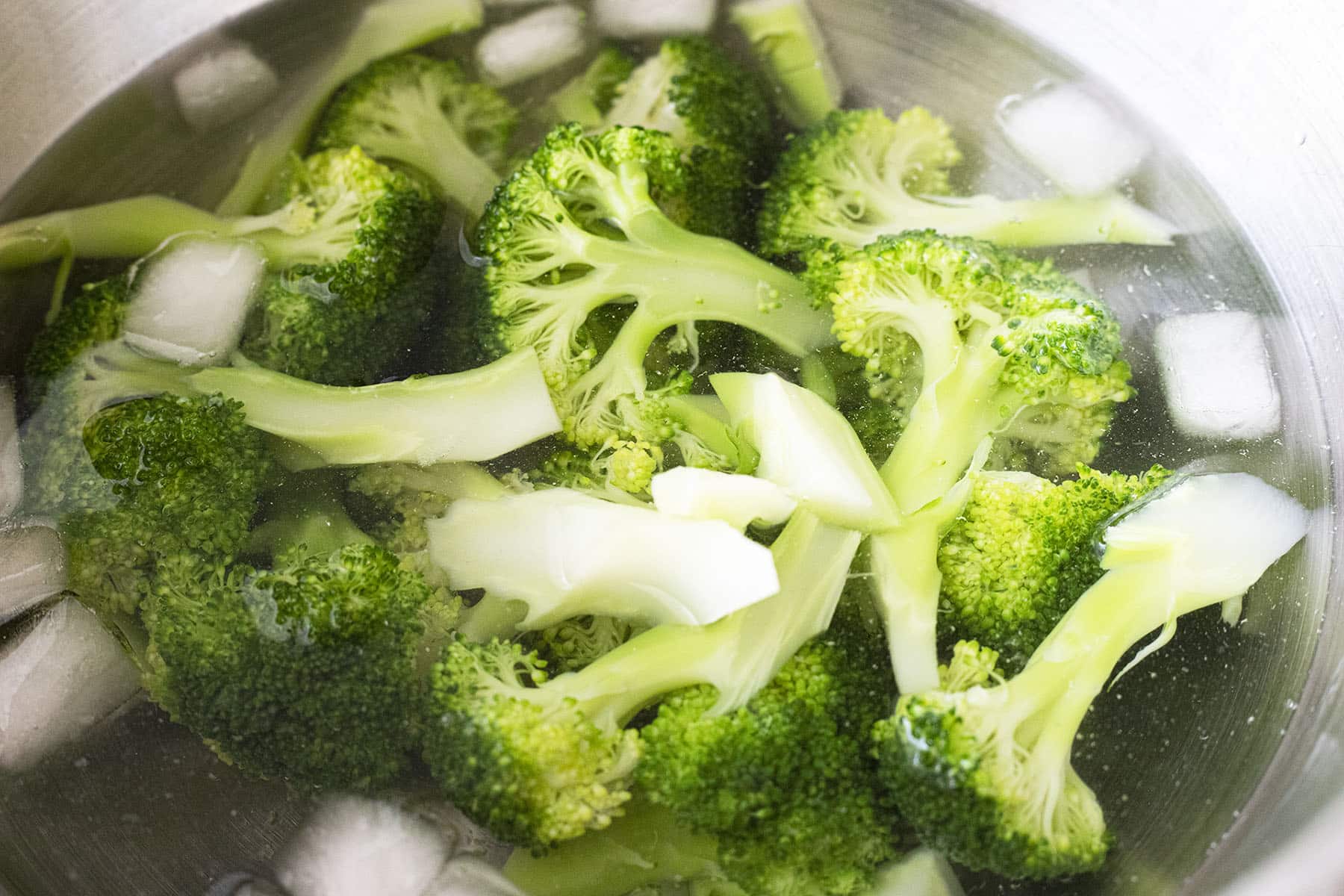 cooked broccoli in bowl of ice water
